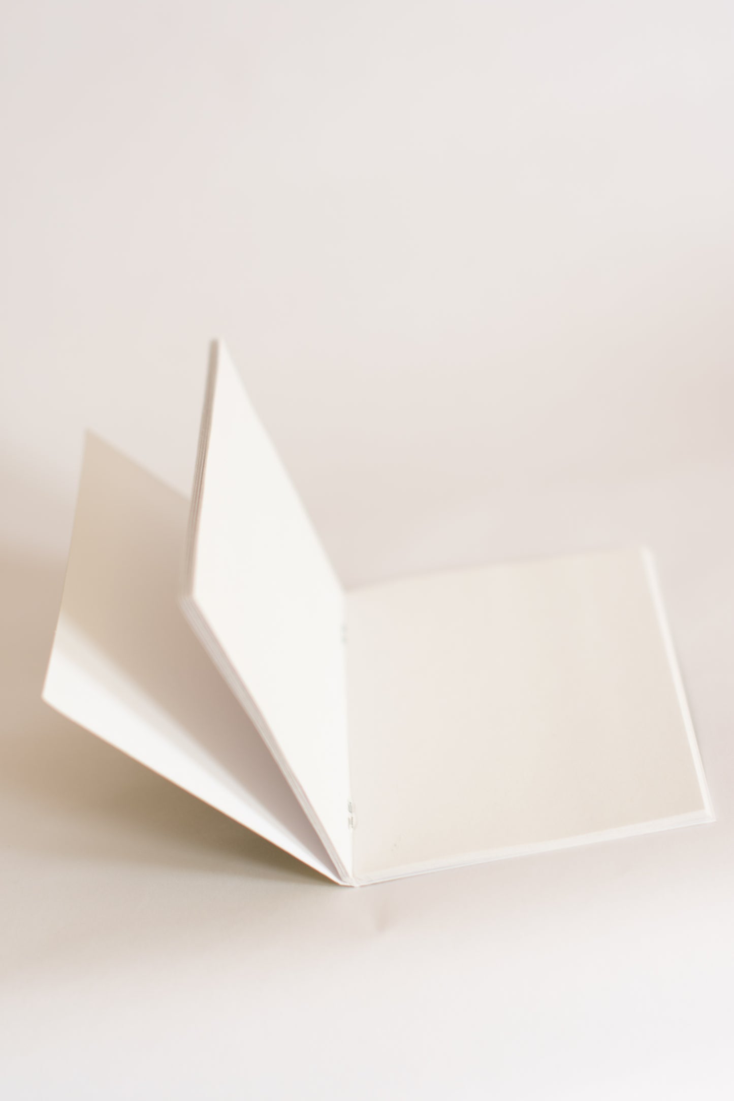 White paper notebook folded open on a light beige background