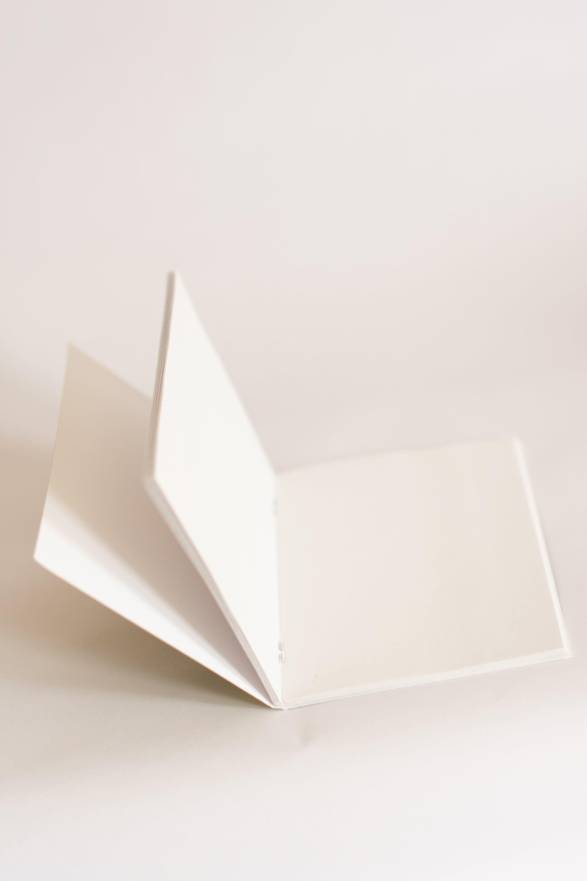 White paper notebook folded open on a light beige background