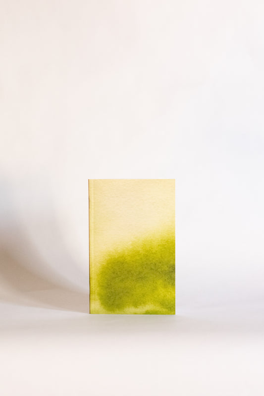 Notebook covered in abstract art with a gradient from yellow to green on a white background