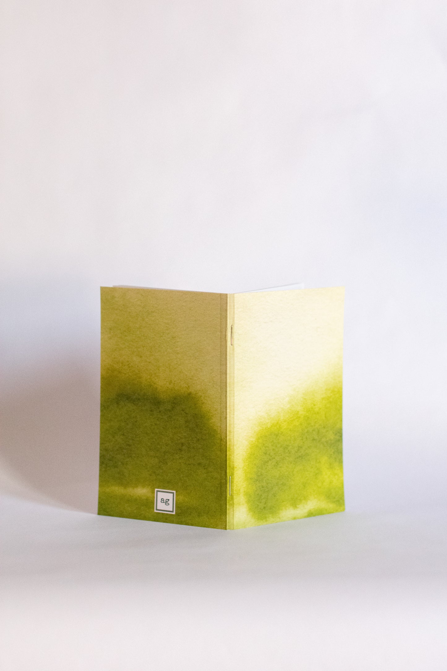 Notebook folded with a cover of abstract green gradient on a white background