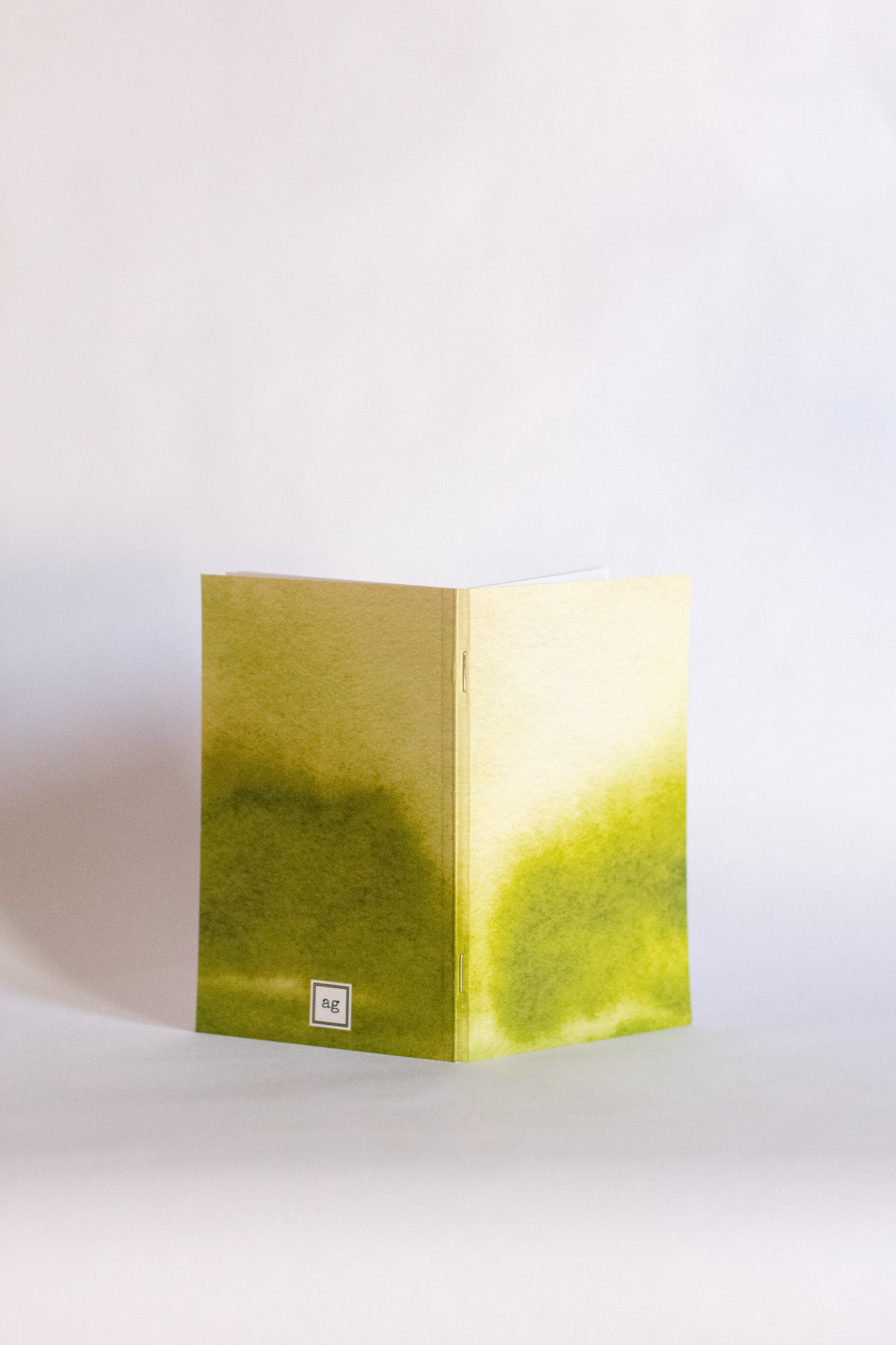 Notebook folded with a cover of abstract green gradient on a white background